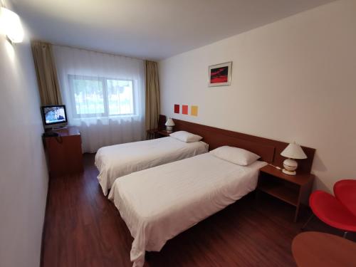a hotel room with two beds and a television at Hotel Timisoara Sannicolau Mare in Sînnicolau Mare