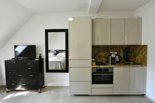 a kitchen with white cabinets and a television and a mirror at Bed&Bike Prachatice in Prachatice