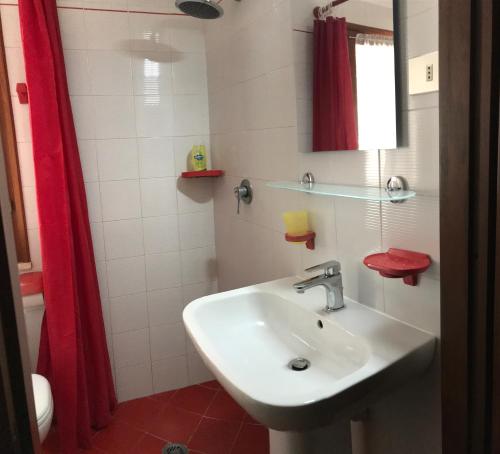 a bathroom with a sink and a red shower curtain at Villetta Straccoligno in Capoliveri