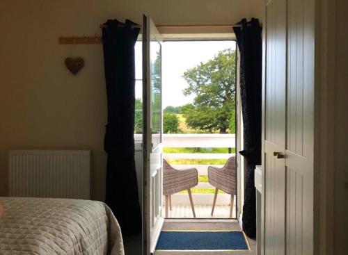 a bedroom with a door open to a balcony with a bed at Moorhouse Farm Flat in Telford