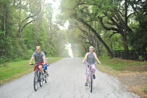 un homme et une femme voyageant à vélo sur une route avec un enfant dans l'établissement The Harmony Oaks Homestead, à Masaryktown