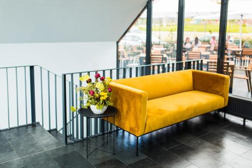 a yellow couch on a balcony with a table with flowers at Hotel Subcarpati in Curtea de Argeş