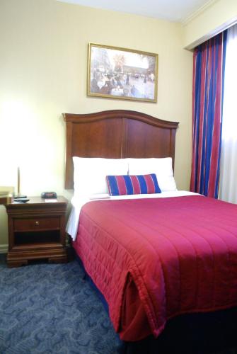 a bedroom with a large bed with a red blanket at Ramada by Wyndham Jersey City in Jersey City