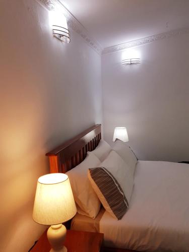 a bedroom with a bed with two lamps and a table at Chinyonga Guesthouse in Limbe