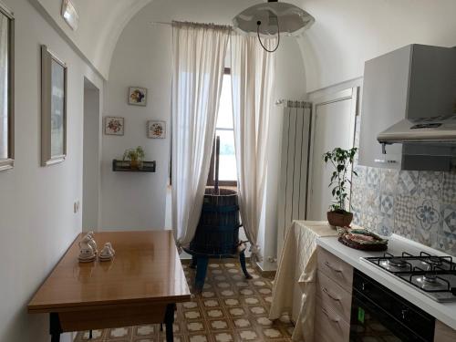 uma cozinha com uma mesa, um fogão e uma janela em masseria chianca " Le Gravine" em Mottola