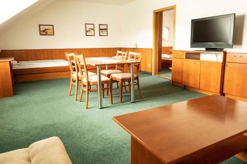 a room with a table and chairs and a television at Penzion Rondo in Bystřice pod Hostýnem