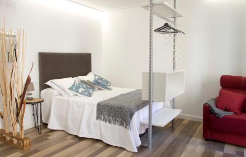 a bedroom with a bed and a red chair at Acio blanco. Loft en el Casco Histórico de Ourense in Ourense