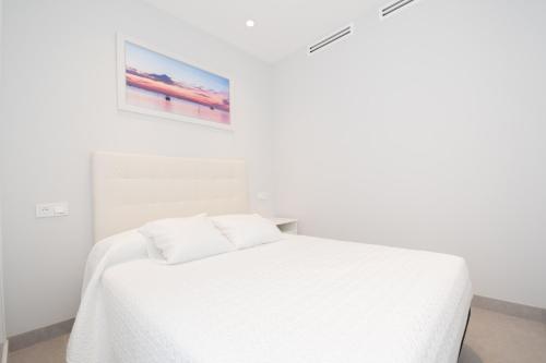 um quarto branco com uma cama branca e um quadro em Cubo's Apartamento Tivoli B4 em Benalmádena