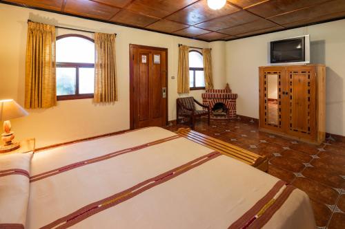 a bedroom with a large bed and a tv in it at Regis Hotel Spa in Panajachel