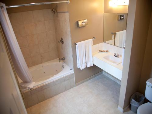 a bathroom with a bath tub and a sink at Hotel Senator in Saskatoon