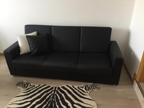 a black couch in a living room with a zebra rug at Apart FL in Mirandela