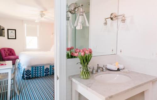uma casa de banho com um lavatório e um vaso de tulipas cor-de-rosa em The Star Inn em Cape May