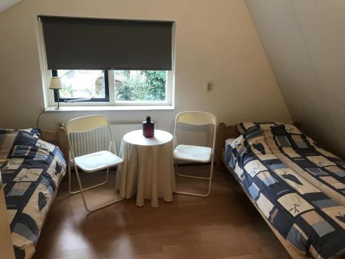 een kamer met twee bedden en een tafel en twee stoelen bij Anna in Nunspeet