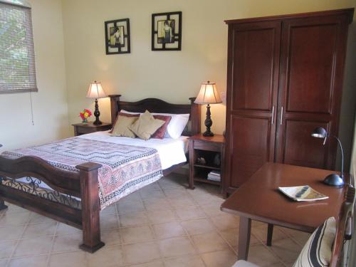 ein Schlafzimmer mit einem Bett, zwei Nachttischen und einem Tisch in der Unterkunft Paloma in Ojochal