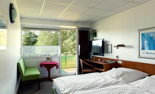 1 dormitorio con cama, escritorio y ventana en Hotel Schleifmühle, en Holzminden