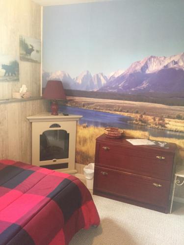 a bedroom with a painting of a mountain range at Silvern Lake Trail Bed and Breakfast in Smithers