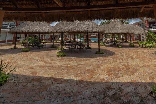 a patio with tables and chairs and straw umbrellas at Hotel Plaza Palmas in Tuxpan de Rodríguez Cano