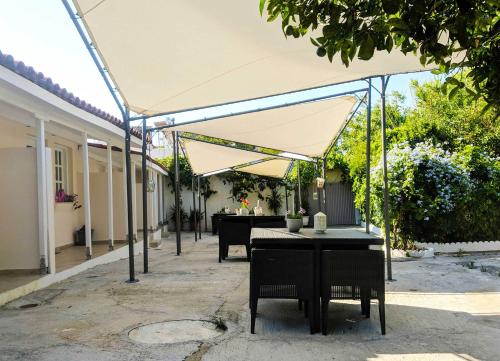 patio ze stołami i krzesłami pod namiotem w obiekcie Hidden garden Deluxe w mieście Skiatos