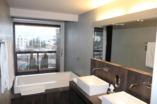 a bathroom with a tub and a sink and a window at Feldmilla Design Hotel - Wellness & SPA in Campo Tures
