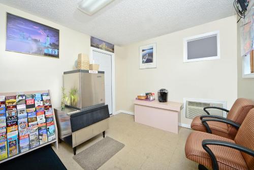 Best Way Inn في Middlefield: غرفة معيشة مع تلفزيون وكراسي وثلاجة