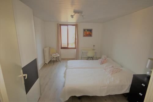 a bedroom with a white bed and a window at Les Narcisses in Blonay