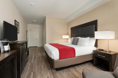 Una habitación de hotel con una cama grande con una manta roja. en Days Inn by Wyndham 100 Mile House, en One Hundred Mile House