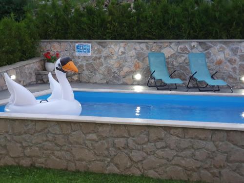 two swans and chairs next to a swimming pool at Villa Kos in Lupoglav