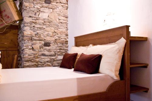 a bed with two pillows and a stone wall at Contrada Beltramelli in Villa di Tirano
