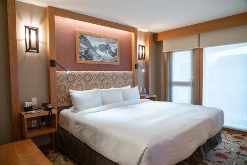 a hotel room with a large bed and a large window at Banff Ptarmigan Inn in Banff