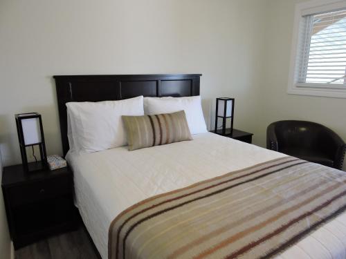 a bedroom with a large white bed with a black headboard at Almo Court Motel in Cranbrook