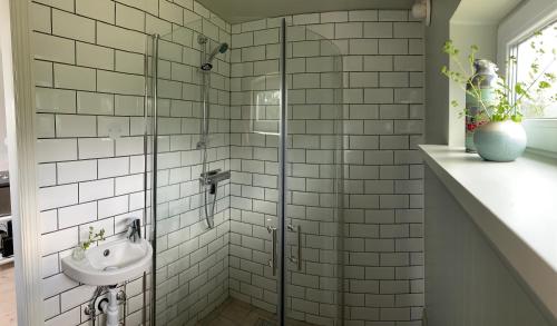 a bathroom with a glass shower with a sink at Station Bed and Kitchen Guesthouse in Varberg