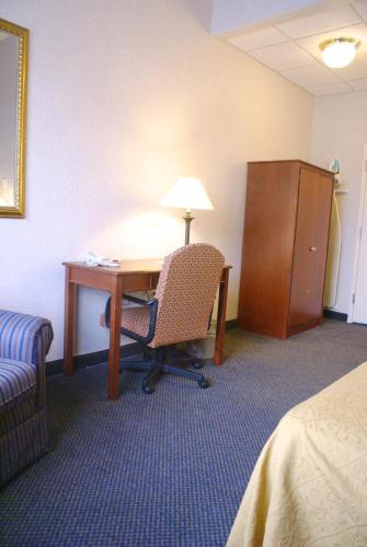 a room with a desk and a chair and a lamp at Raritan Hotel in Edison