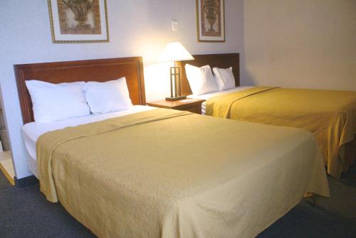 a hotel room with two beds and a lamp at Raritan Hotel in Edison