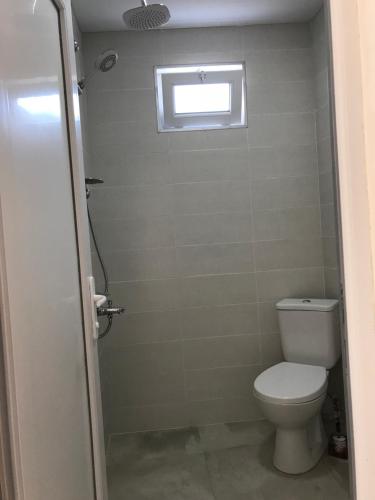 a small bathroom with a toilet and a window at Hotel CHARLI in Gonio