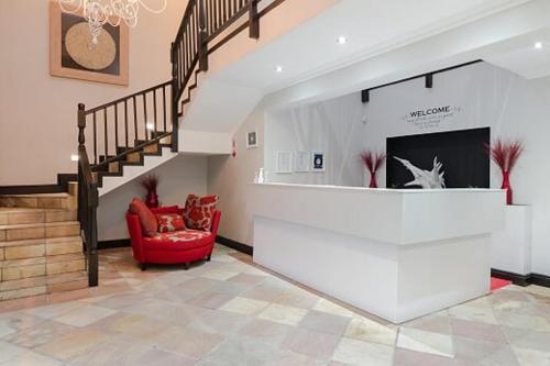 a living room with a staircase and a red chair at 47th on Howard in Knysna