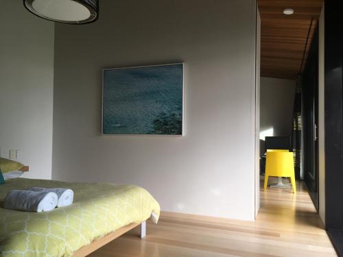 ein Schlafzimmer mit einem Bett und einem Bild an der Wand in der Unterkunft Hot Water Beach Bure Wai in Hotwater Beach