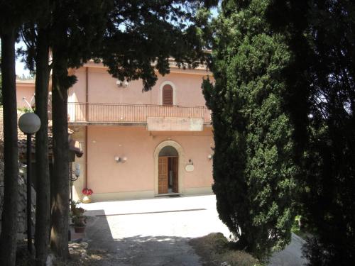 a large pink building with a balcony on top of it at Albergo Villa Nobile in Chiaramonte Gulfi
