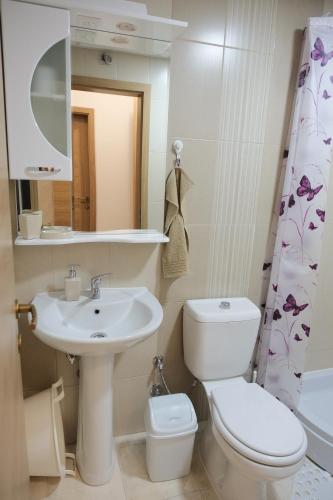 a bathroom with a sink and a toilet and a mirror at Enjoy Apartments Karamach in Ohrid