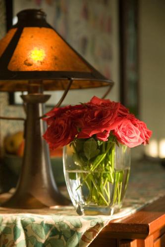 a vase filled with red roses sitting next to a lamp at Lake Pointe Inn in McHenry