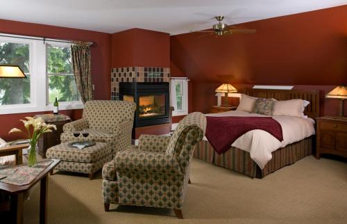 a bedroom with a bed and chairs and a fireplace at Lake Pointe Inn in McHenry