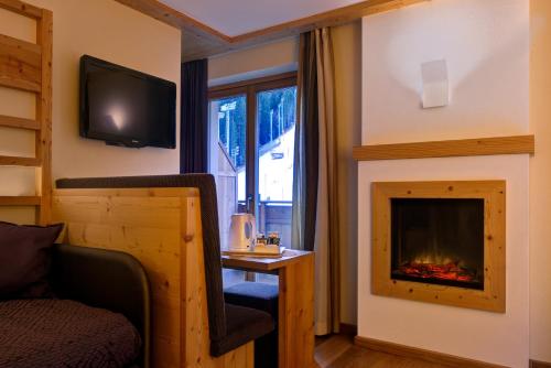a living room with a fireplace and a tv at Boutique Hotel Diana in Madonna di Campiglio