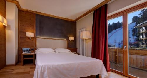 a bedroom with a bed and a large window at Boutique Hotel Diana in Madonna di Campiglio