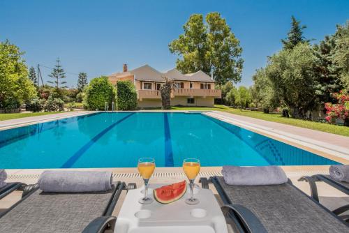una piscina con un tavolo con due bicchieri di succo d'arancia di Leone Luxury Villas a Kalamákion