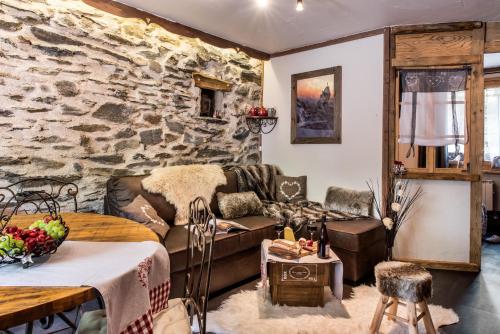 un salon avec un canapé et un mur en pierre dans l'établissement Aux pieds des cimes, à Aime La Plagne