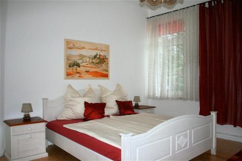 Schlafzimmer mit einem weißen Bett und roten Kissen in der Unterkunft Ferienwohnung am Kurpark in Bad Nenndorf