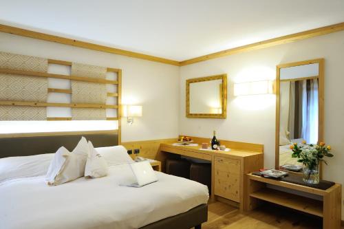 a bedroom with a bed and a sink and a mirror at Boutique Hotel Diana in Madonna di Campiglio