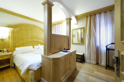 a bedroom with a large bed with a wooden headboard at Boutique Hotel Diana in Madonna di Campiglio