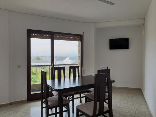 Un comedor con mesa y sillas y una ventana. en Apartamentos O Cargadeiro Ribadeo, en Ribadeo