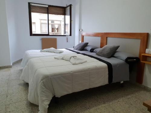 Dos camas en un dormitorio con toallas. en Apartamentos O Cargadeiro Ribadeo, en Ribadeo