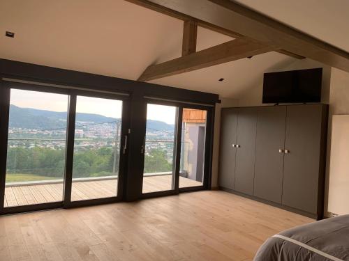 - une chambre avec des portes coulissantes en verre et une grande fenêtre dans l'établissement Gite grand standing dans cadre idyllique, à Saint-Étienne-lès-Remiremont